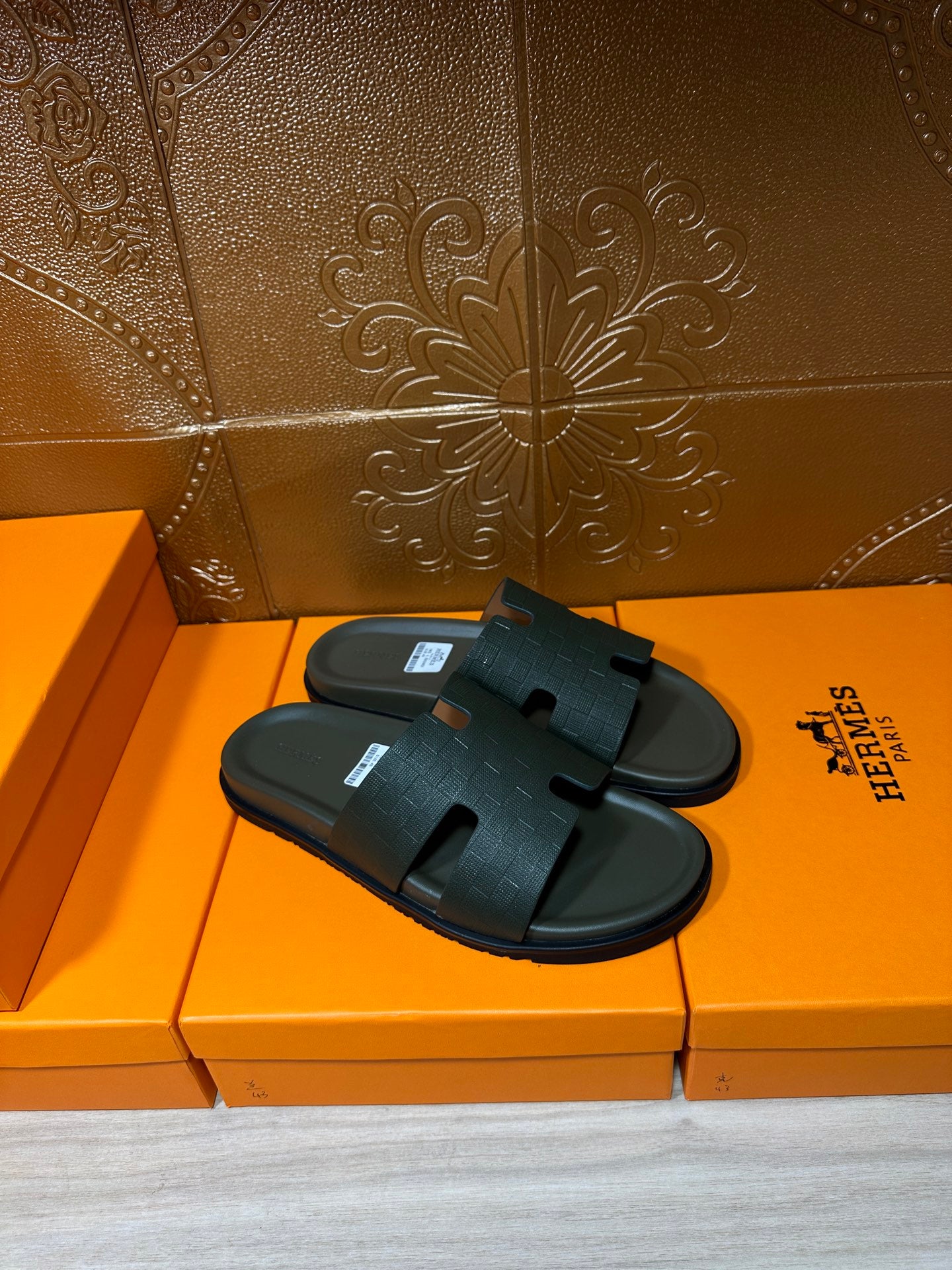 Hermes slide sandals, dark green wide strap and black sole, side view on orange box