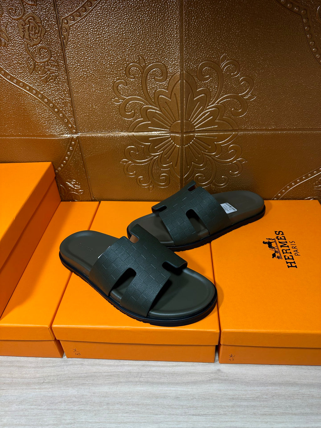 Hermes slide sandals, dark green with embossed strap, front view on orange box