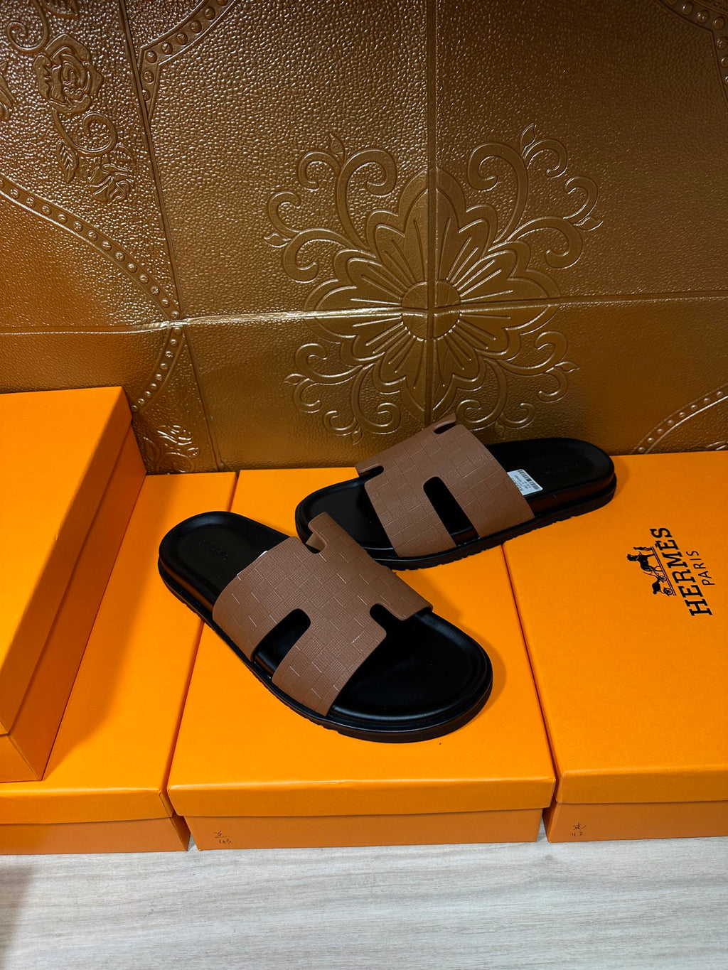 Hermes slide sandals with tan leather strap and black footbed, three-quarter view