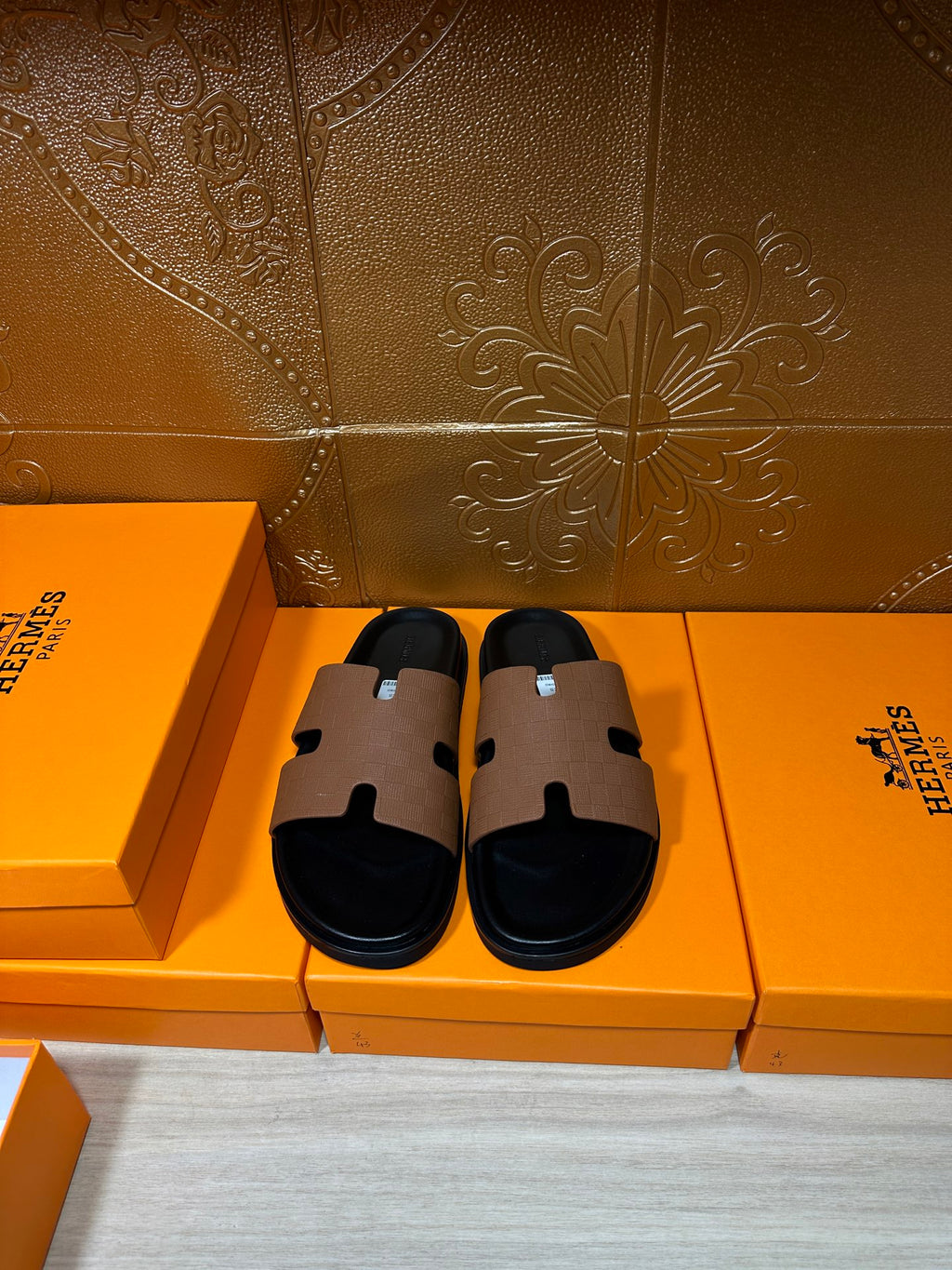 Hermes slide sandals with tan leather strap and black footbed, side-by-side view