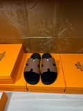 Hermes slide sandals with tan leather strap and black footbed, side-by-side view