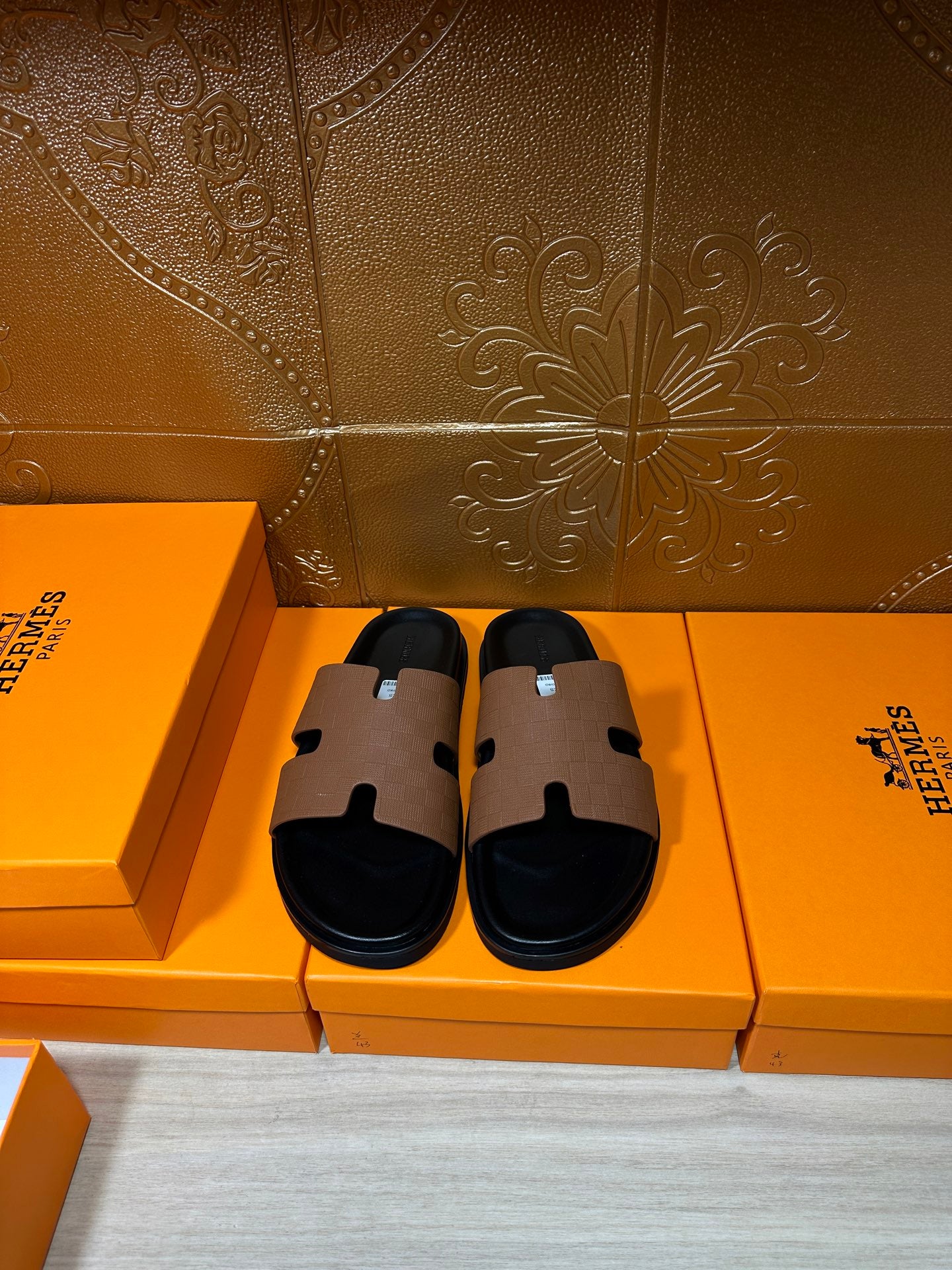 Hermes slide sandals with tan leather strap and black footbed, side-by-side view