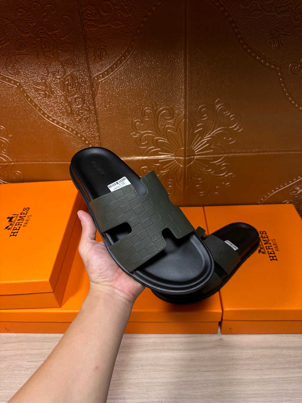Hermes black slide sandal held in hand, textured wide strap and flat sole