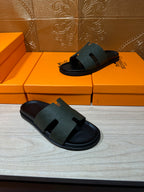 Hermes black slide sandals on boxes, one pair shown with textured wide strap
