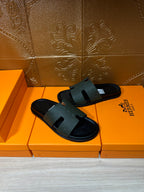 Hermes black slide sandals with textured straps and open toe, flat sole