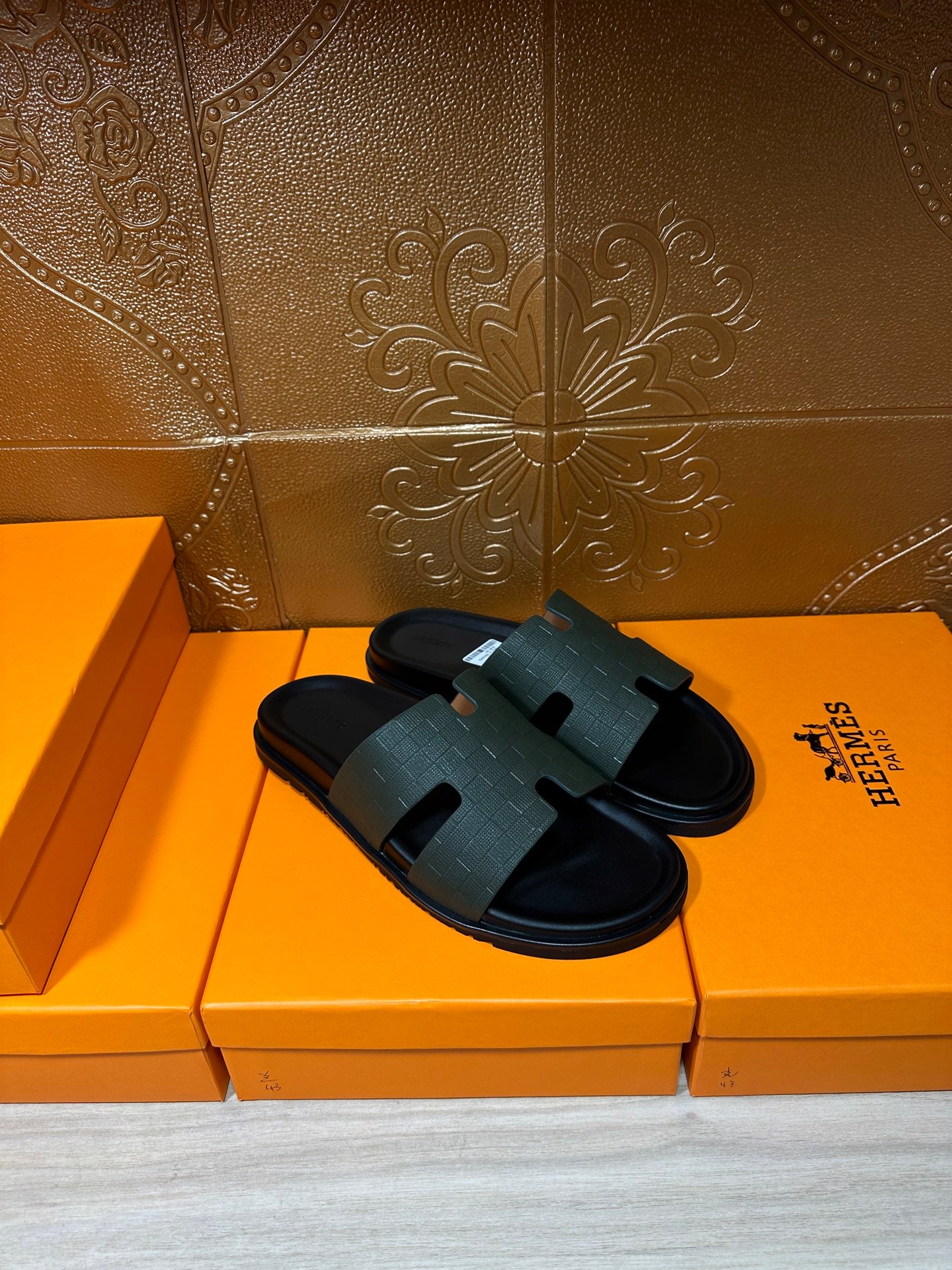 Hermes black slide sandals resting on boxes, wide strap and flat rubber sole