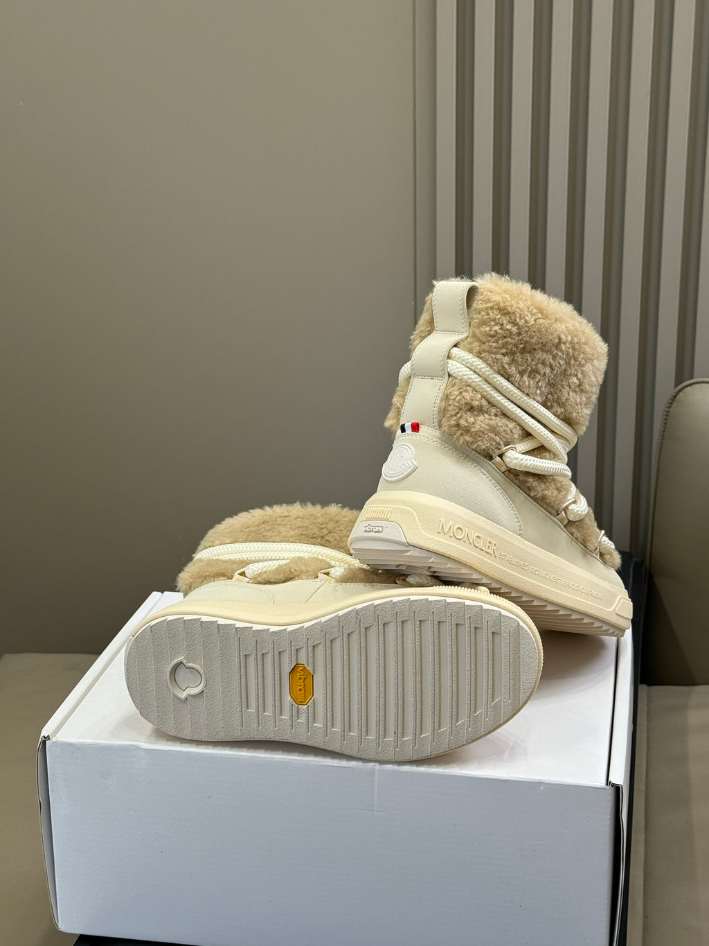 Moncler shearling boots with light tan upper, visible tread sole, and white laces