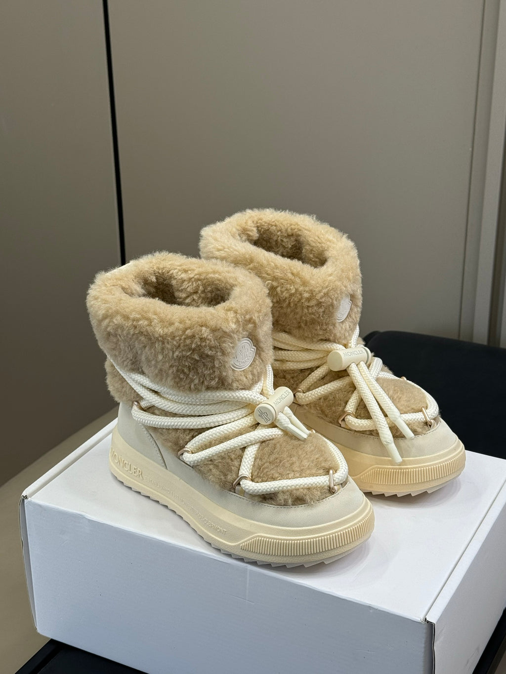Pair of Moncler shearling boots with light tan fuzzy cuffs and white lace-up front