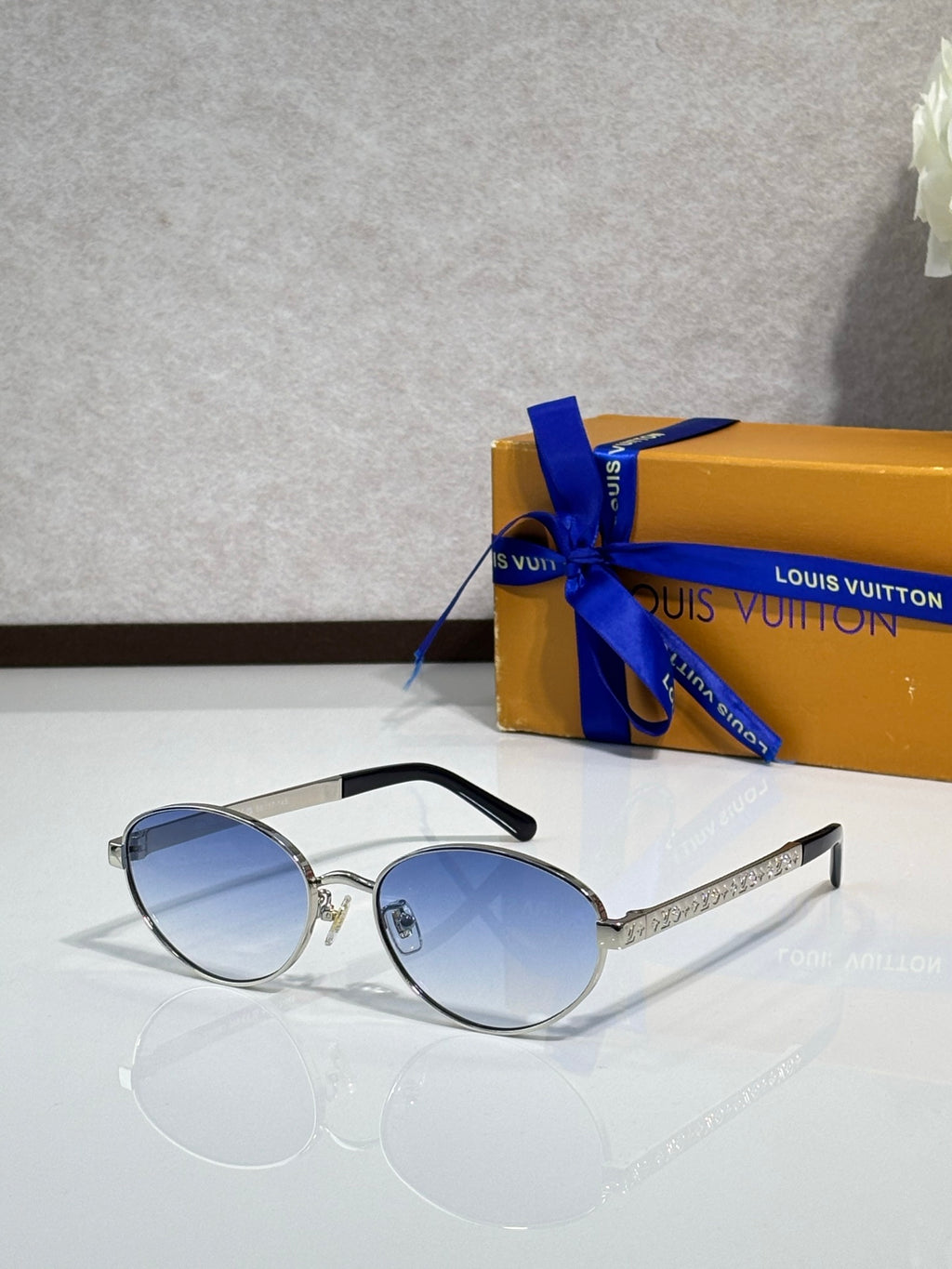Silver round sunglasses with blue-tinted lenses and clear temple tips