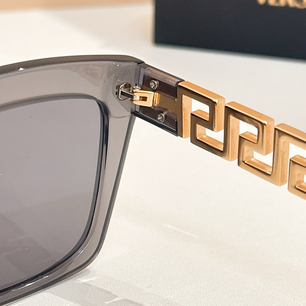 Gold logo hinge detail on clear gray sunglasses frame