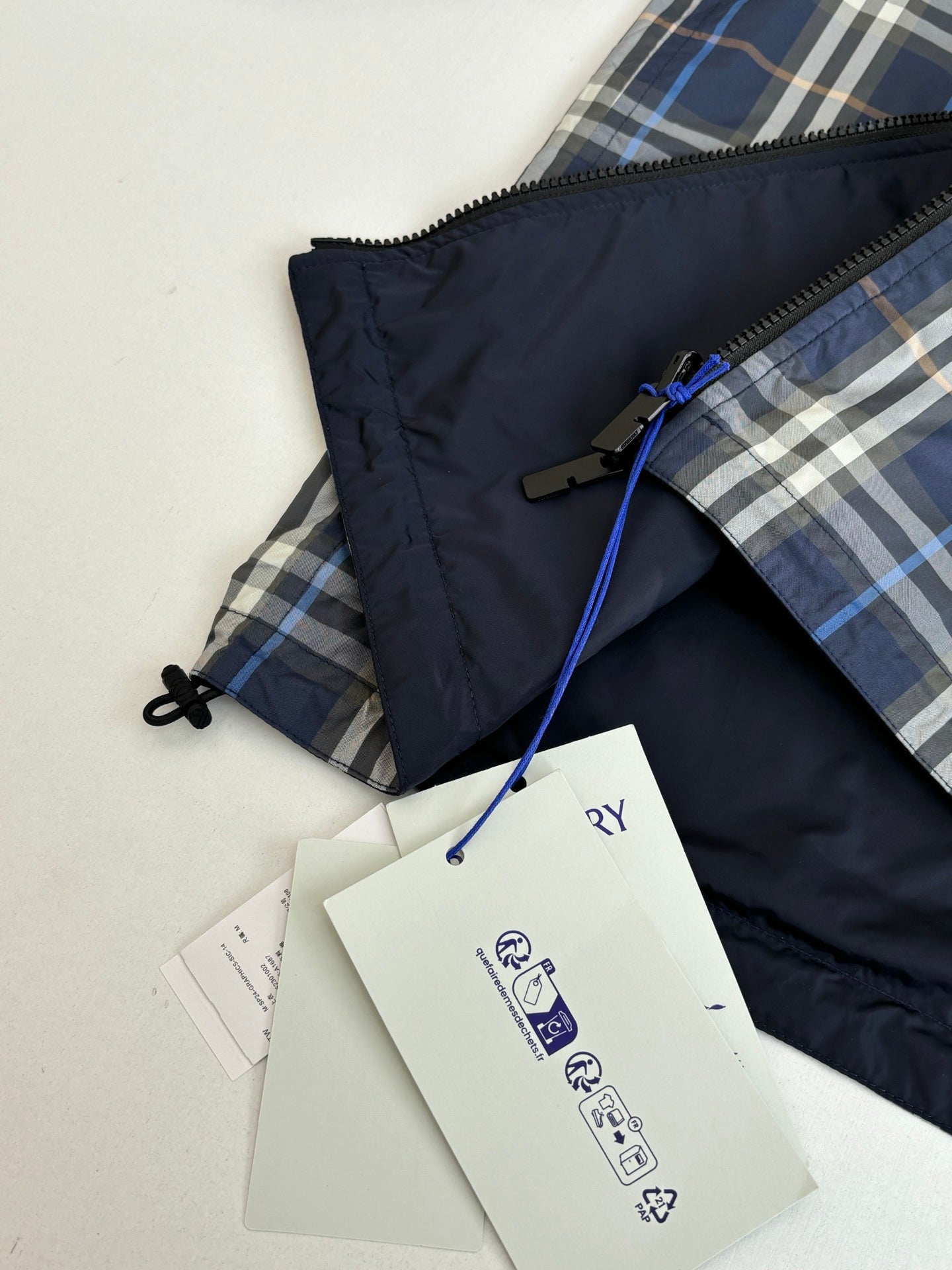 Burberry long jacket with navy body, plaid lining, and drawstring hood
