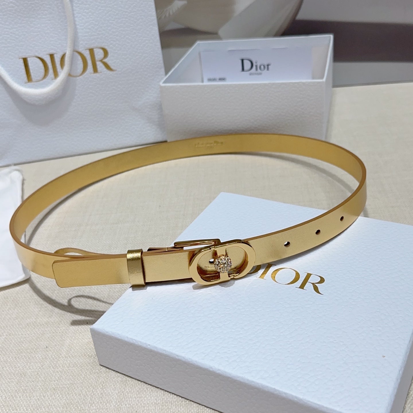 Dior gold-tone leather belt with oval buckle, rhinestone center, and adjustable holes