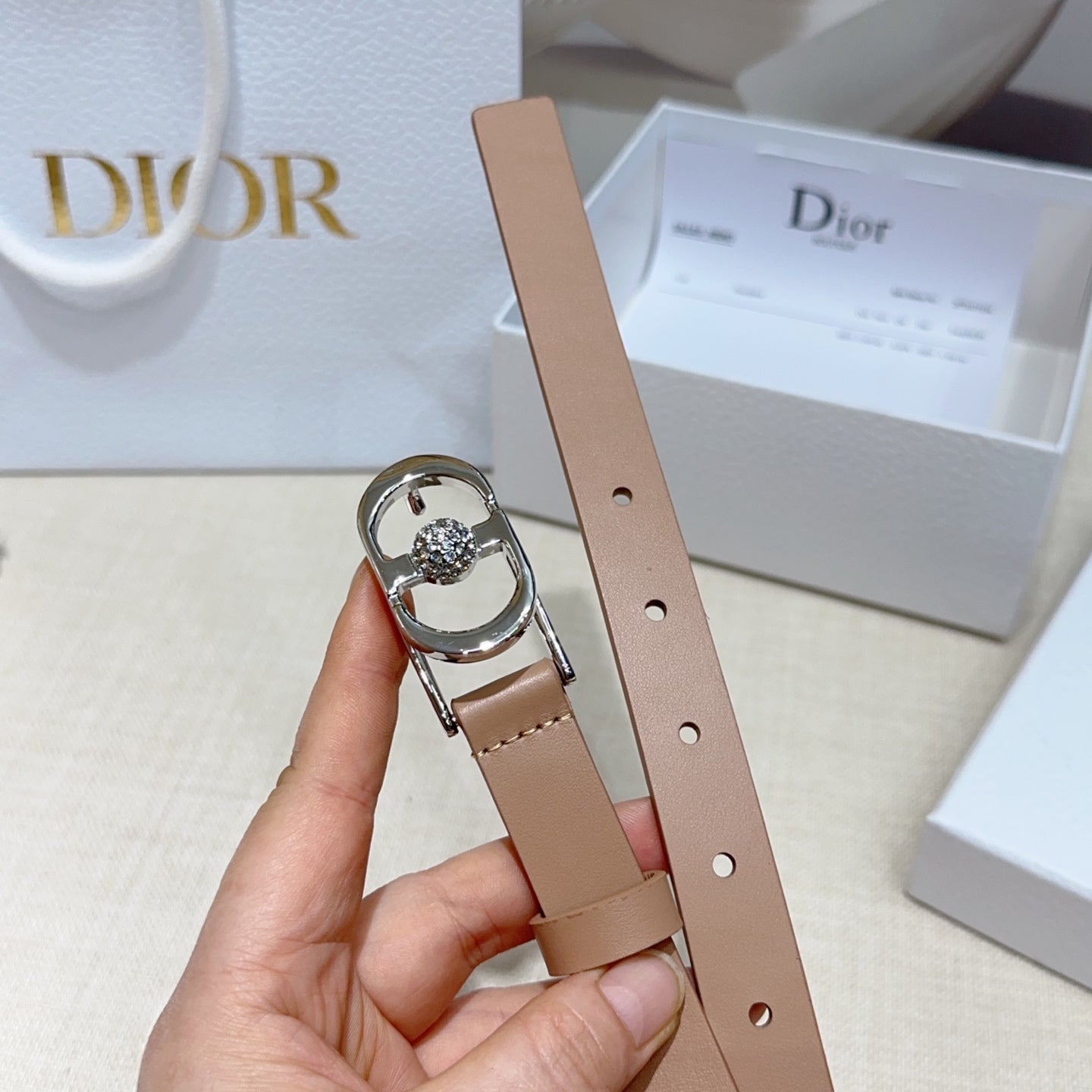 Tan leather belt with silver buckle and gem centerpiece, held up