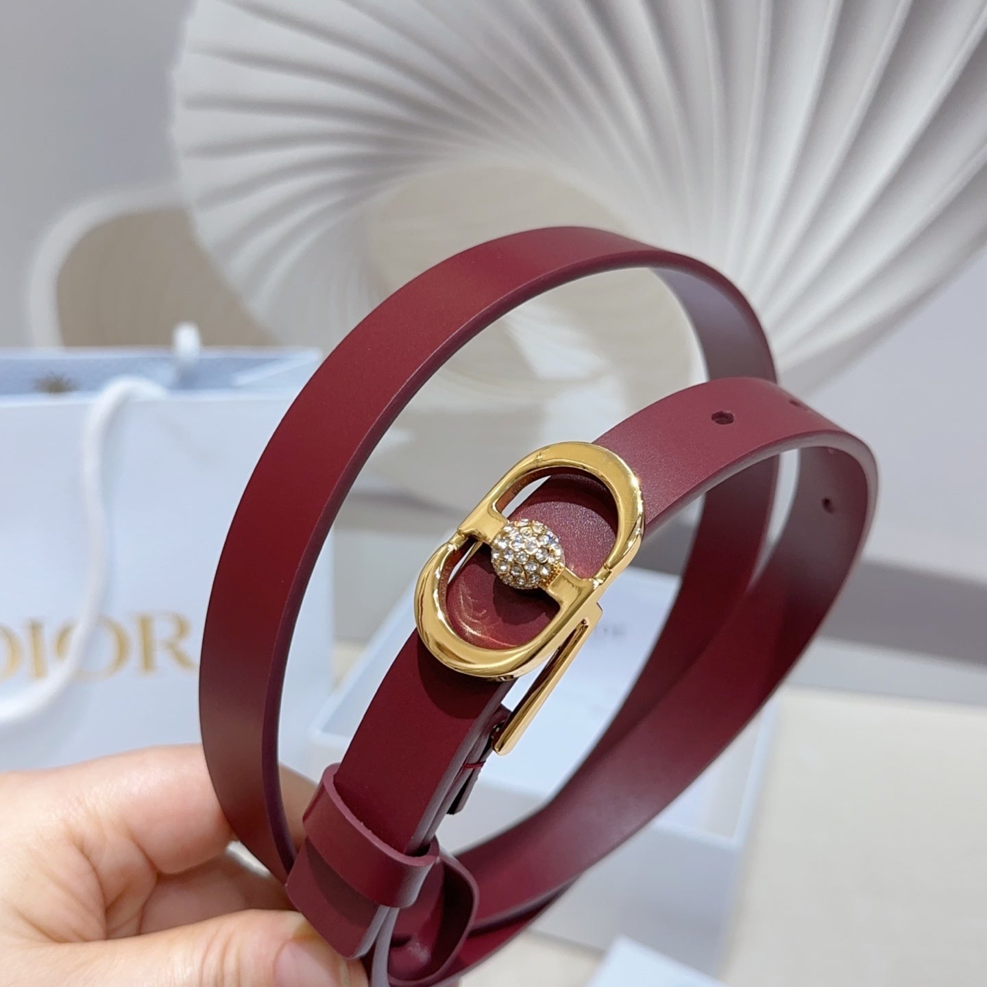 Burgundy leather belt with gold-tone buckle and round crystal charm