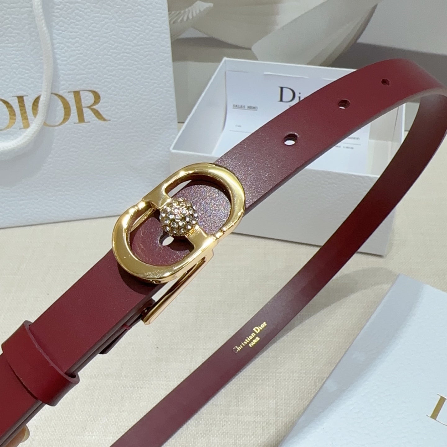 Burgundy leather belt close-up with gold-tone buckle and crystal heart charm