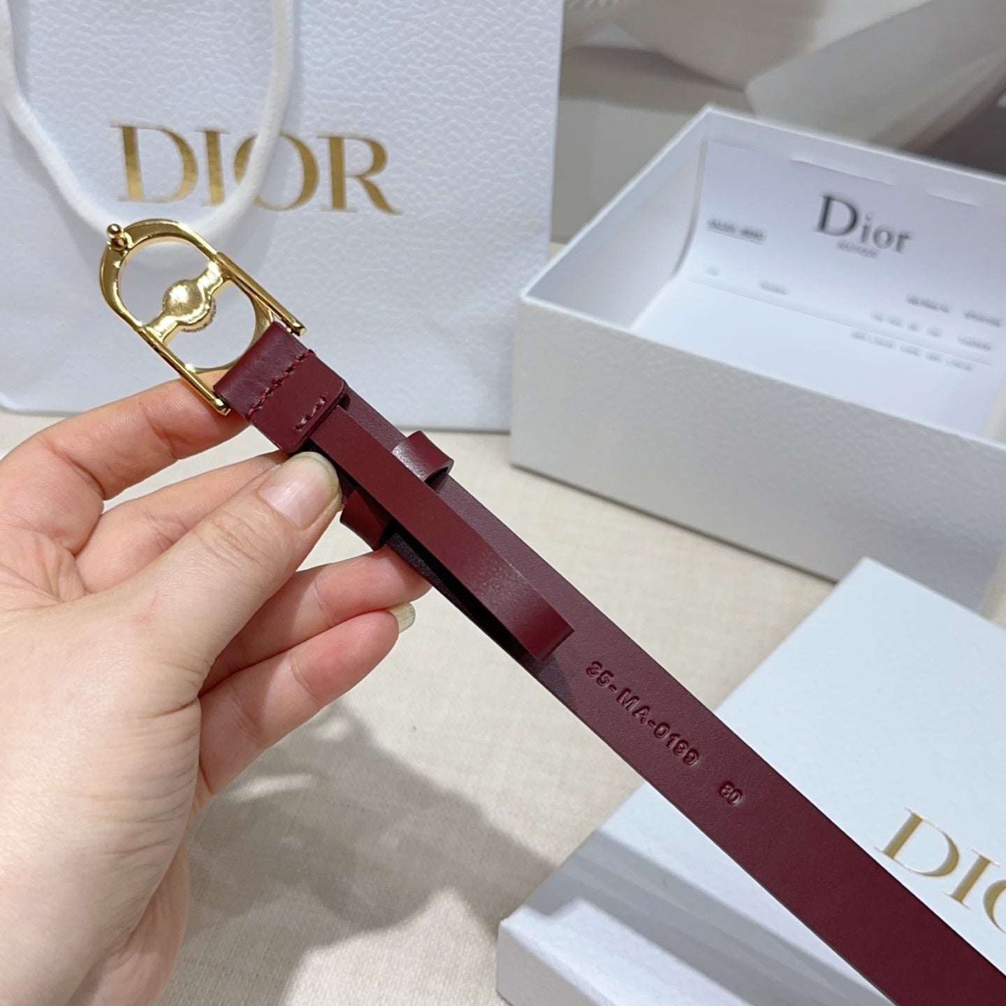 Burgundy leather belt with gold-tone buckle and crystal charm detail