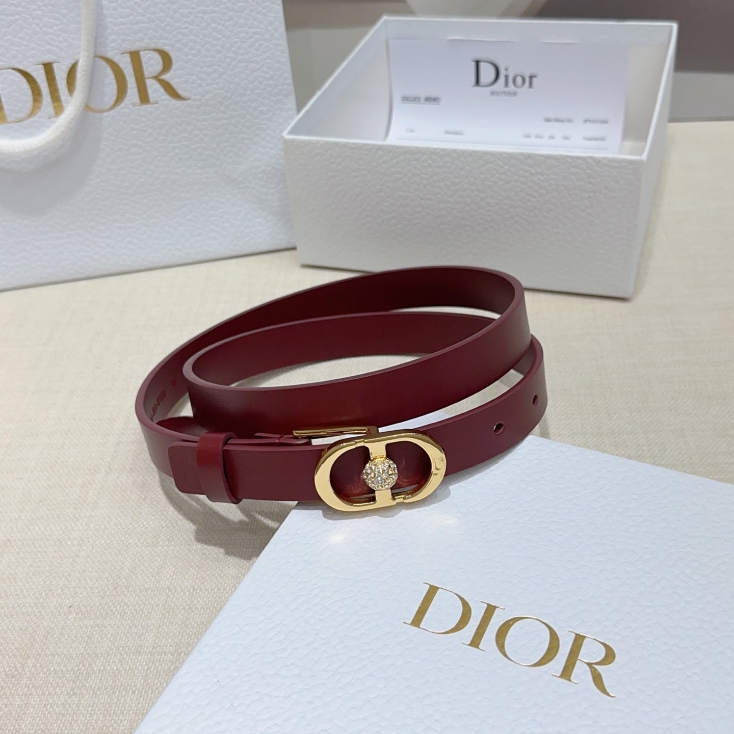 Burgundy leather belt with gold-tone buckle and crystal charm on strap