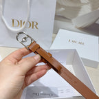 Tan leather belt with silver buckle and crystal charm, held in hand