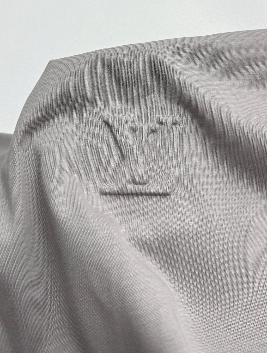 Light gray T-shirt with embossed-style LV emblem near upper back