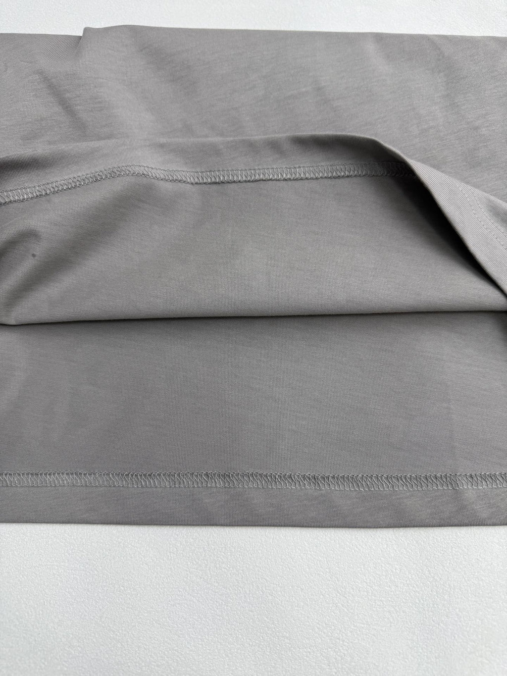 Light gray T-shirt fabric with stitched hem and side seam detail