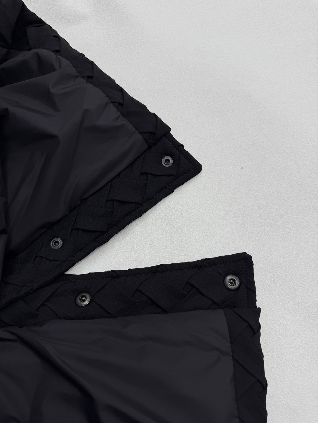 Black jacket cuff with snap strap and woven-texture trim