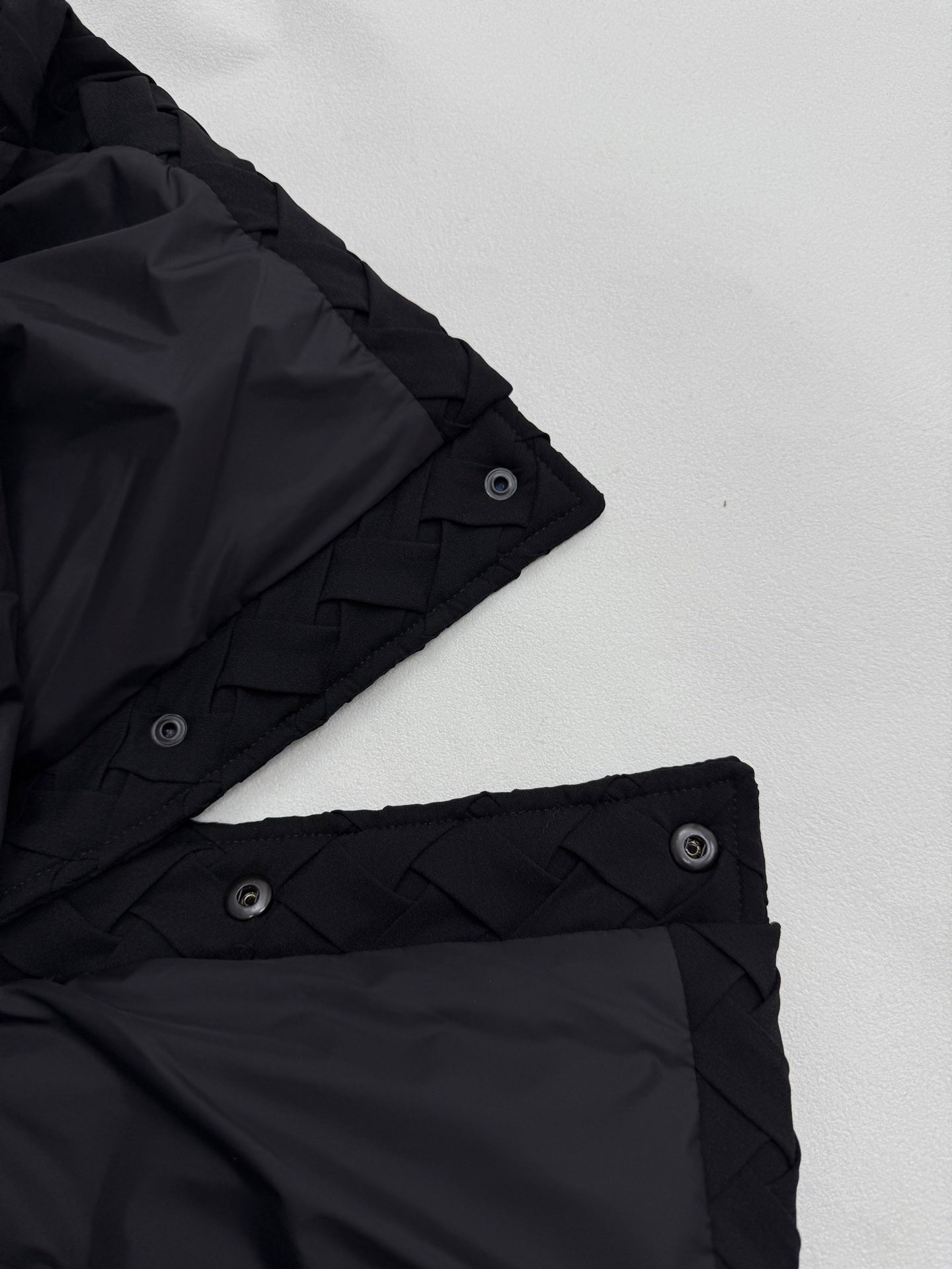 Black jacket cuff with snap strap and woven-texture trim