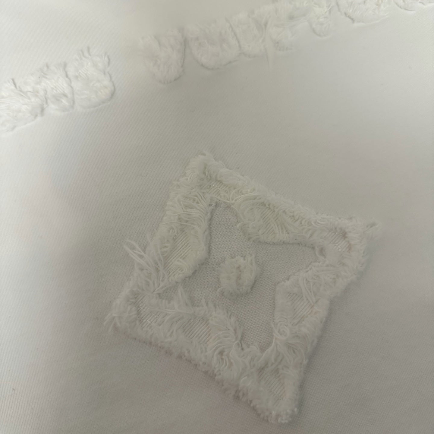 White T-shirt textured embroidered emblem close-up