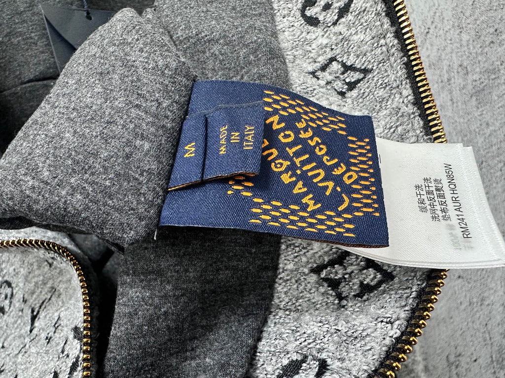 Louis Vuitton hooded jacket interior tag and blue label near zipper, on gray fabric