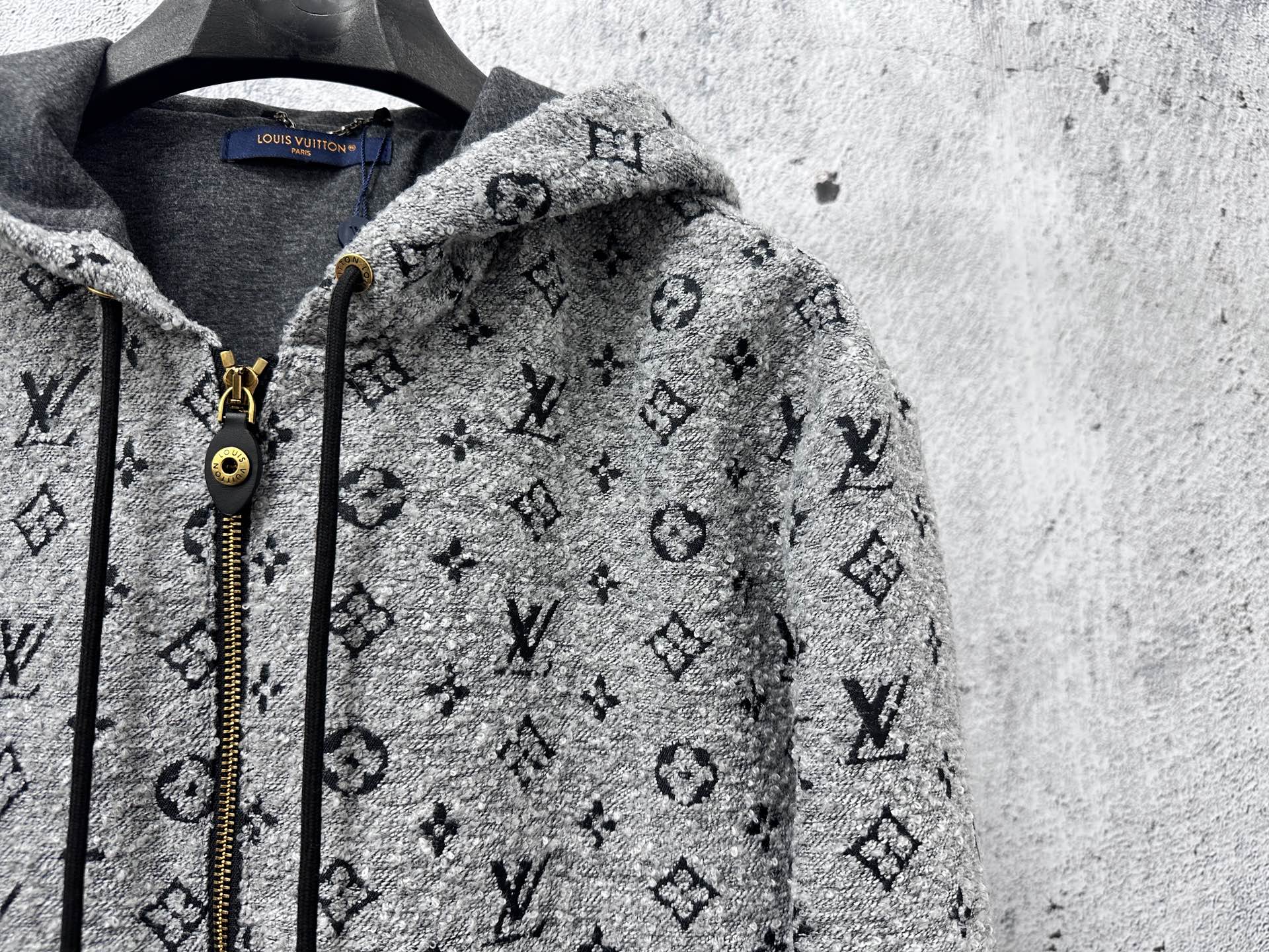 Louis Vuitton hooded jacket close-up: dark gray monogram print, zipper and cord pulls