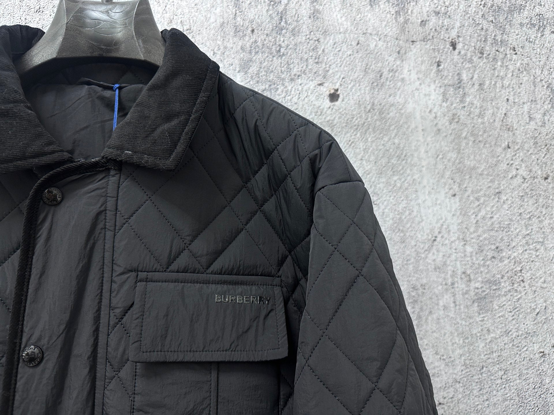 Burberry long quilted jacket chest pocket with logo patch on dark fabric