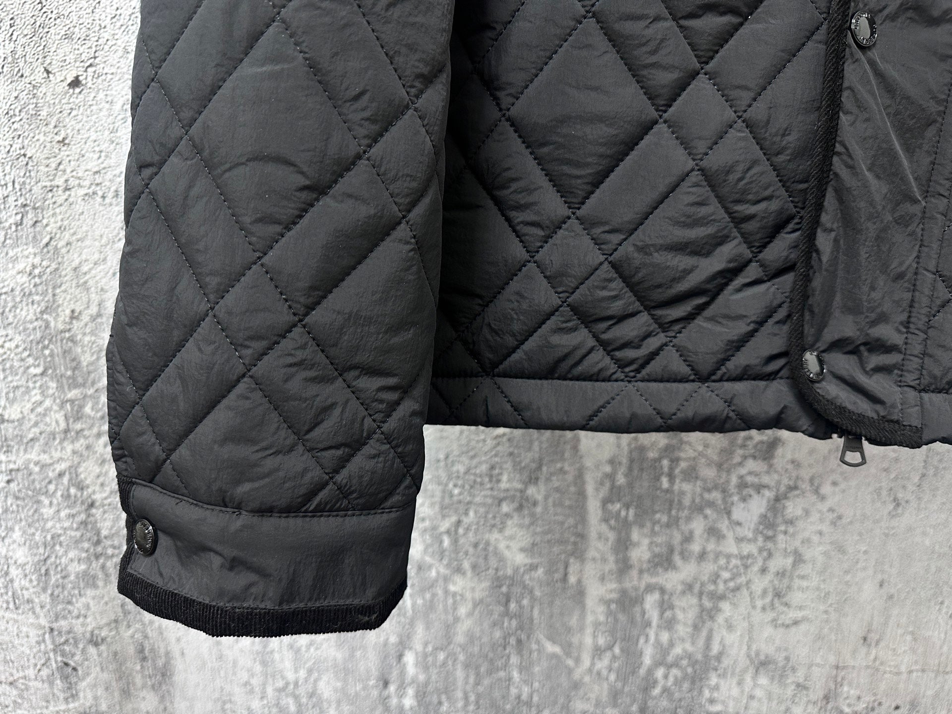 Burberry long quilted jacket side view with ribbed sleeve cuff and button