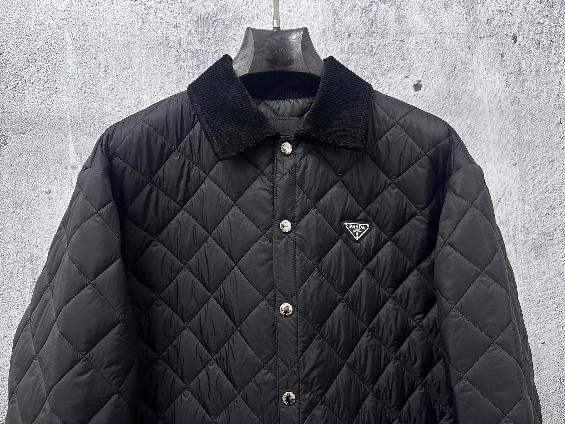 Prada quilted long jacket in dark black with chest logo and snap front