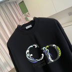 Black crewneck sweatshirt close-up with colorful crest graphic print