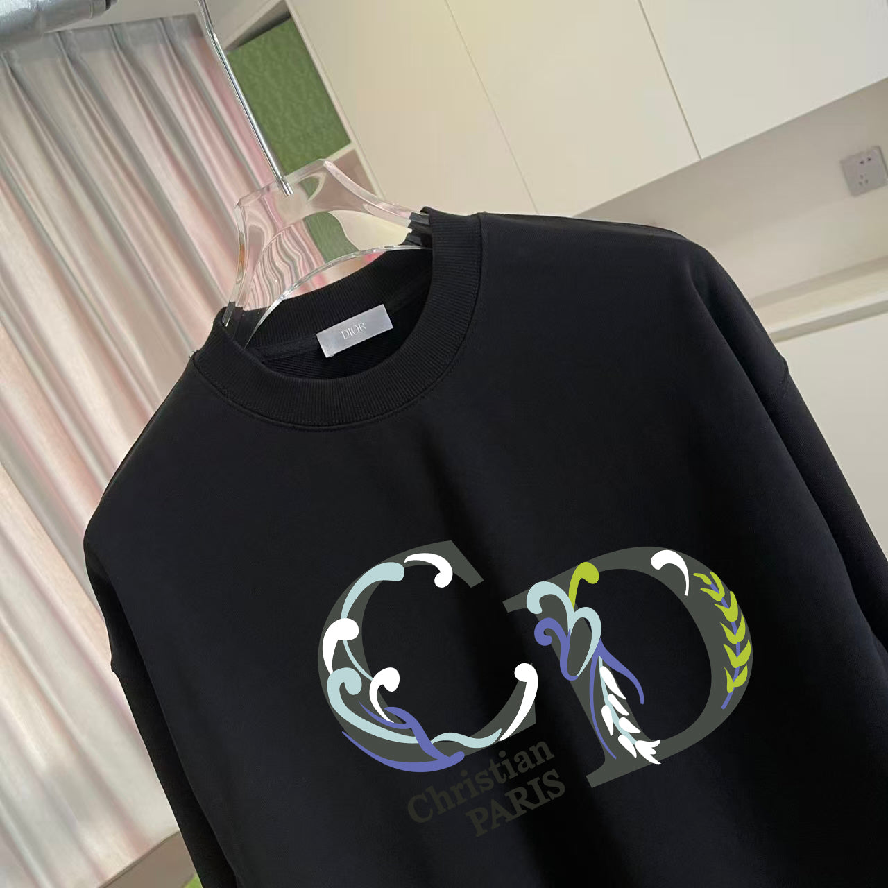 Black crewneck sweatshirt close-up with colorful crest graphic print