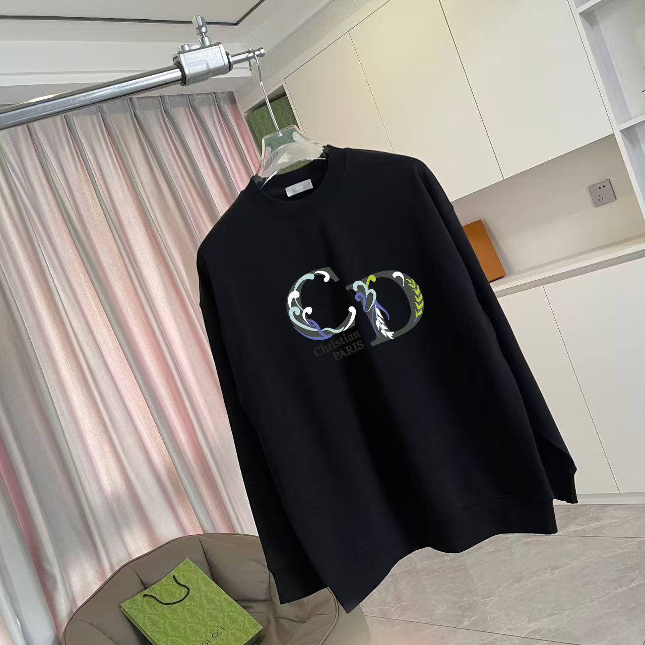 Black long-sleeve crewneck sweatshirt with colorful crest graphic print, angled