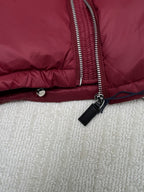 Long padded jacket detail: silver zip, black tag pull, snap waist button