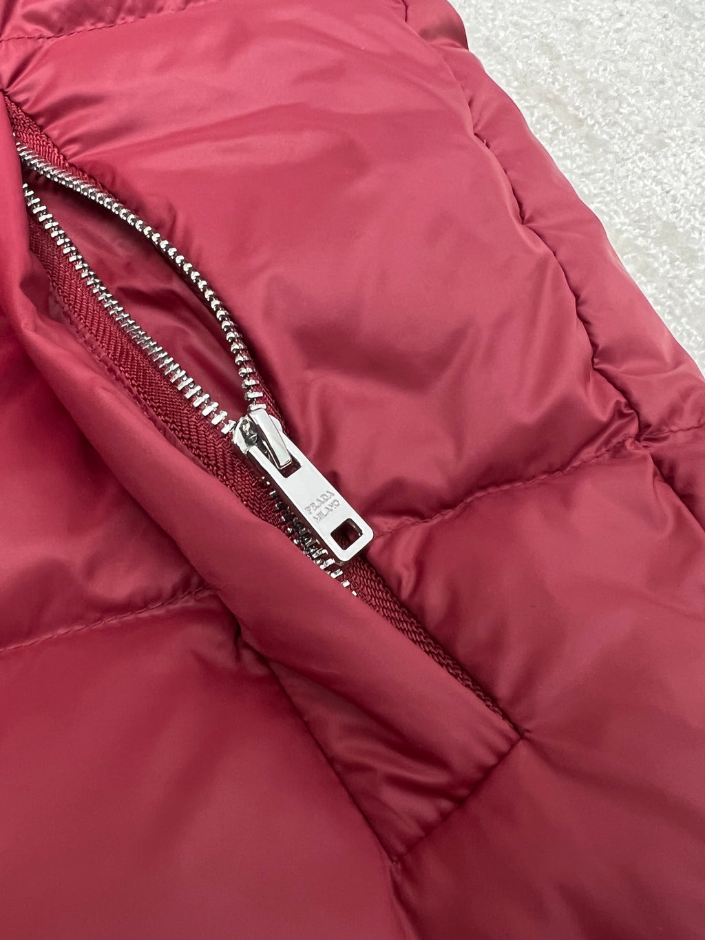 Prada red puffer jacket close-up of front zipper and fabric paneling
