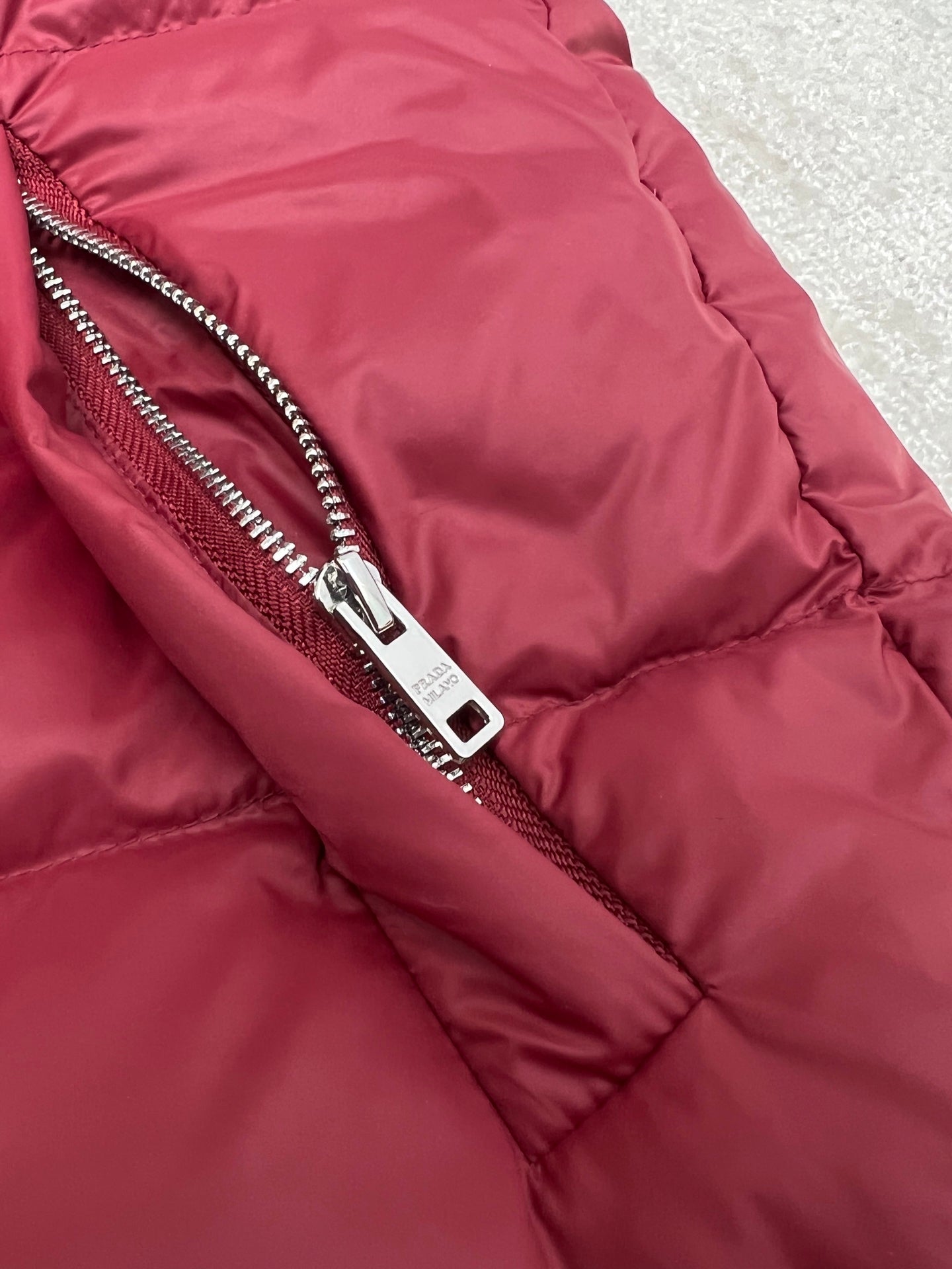 Prada red puffer jacket close-up of front zipper and fabric paneling