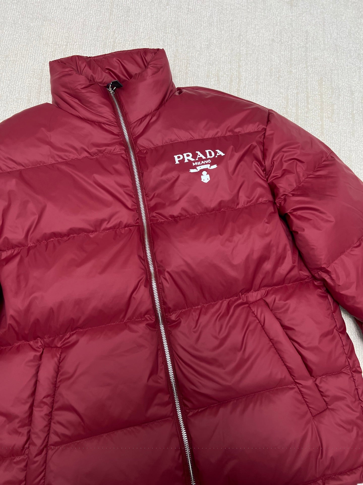 Prada red puffer jacket with stand collar, front zipper, and PRADA logo