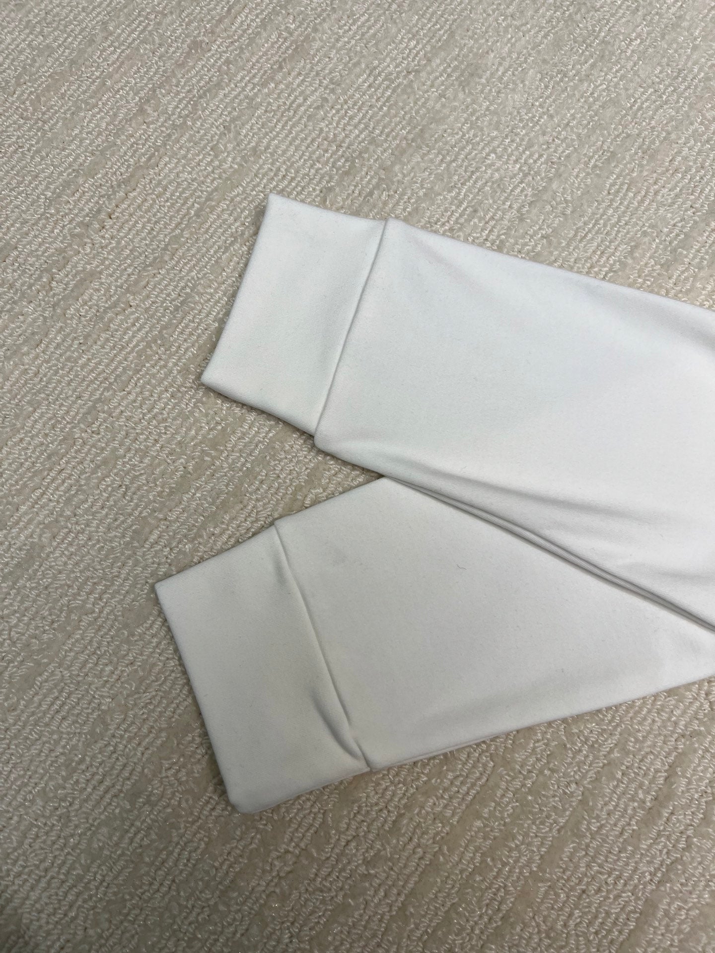 White long-sleeve shirt folded flat on textured surface