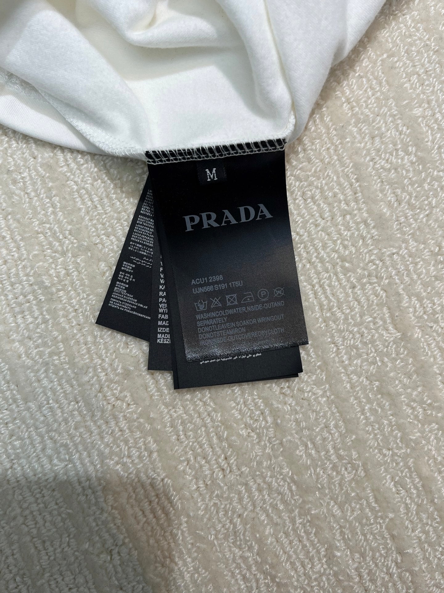 White long-sleeve shirt with size M and PRADA care label at neckline
