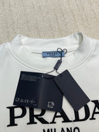 White crewneck shirt with PRADA logo at chest and attached hang tag