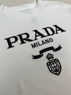 White long-sleeve shirt detail: PRADA MILANO lettering and crest emblem