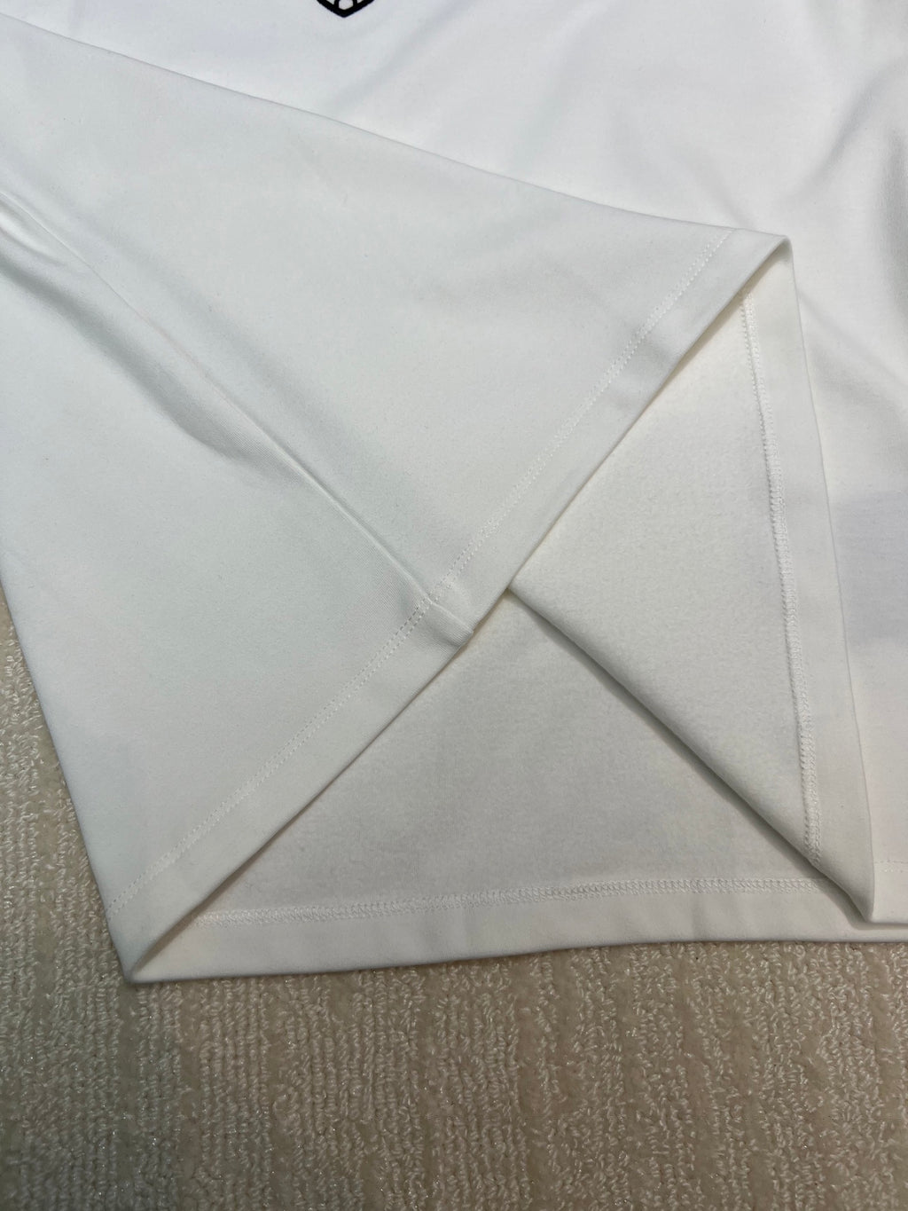 White long-sleeve shirt sleeve and hem seam detail