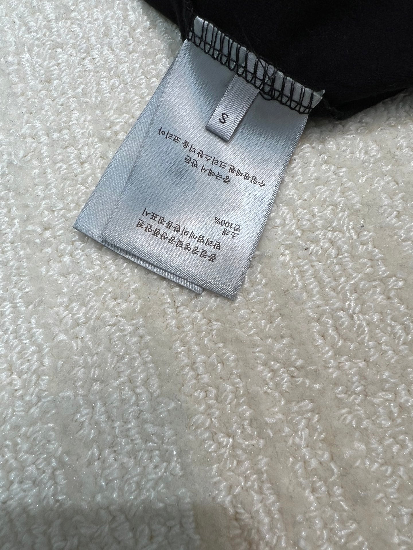 Size and care label on dark sweatshirt, marked S
