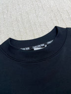 Dark crewneck sweatshirt neckline with small brand print inside collar