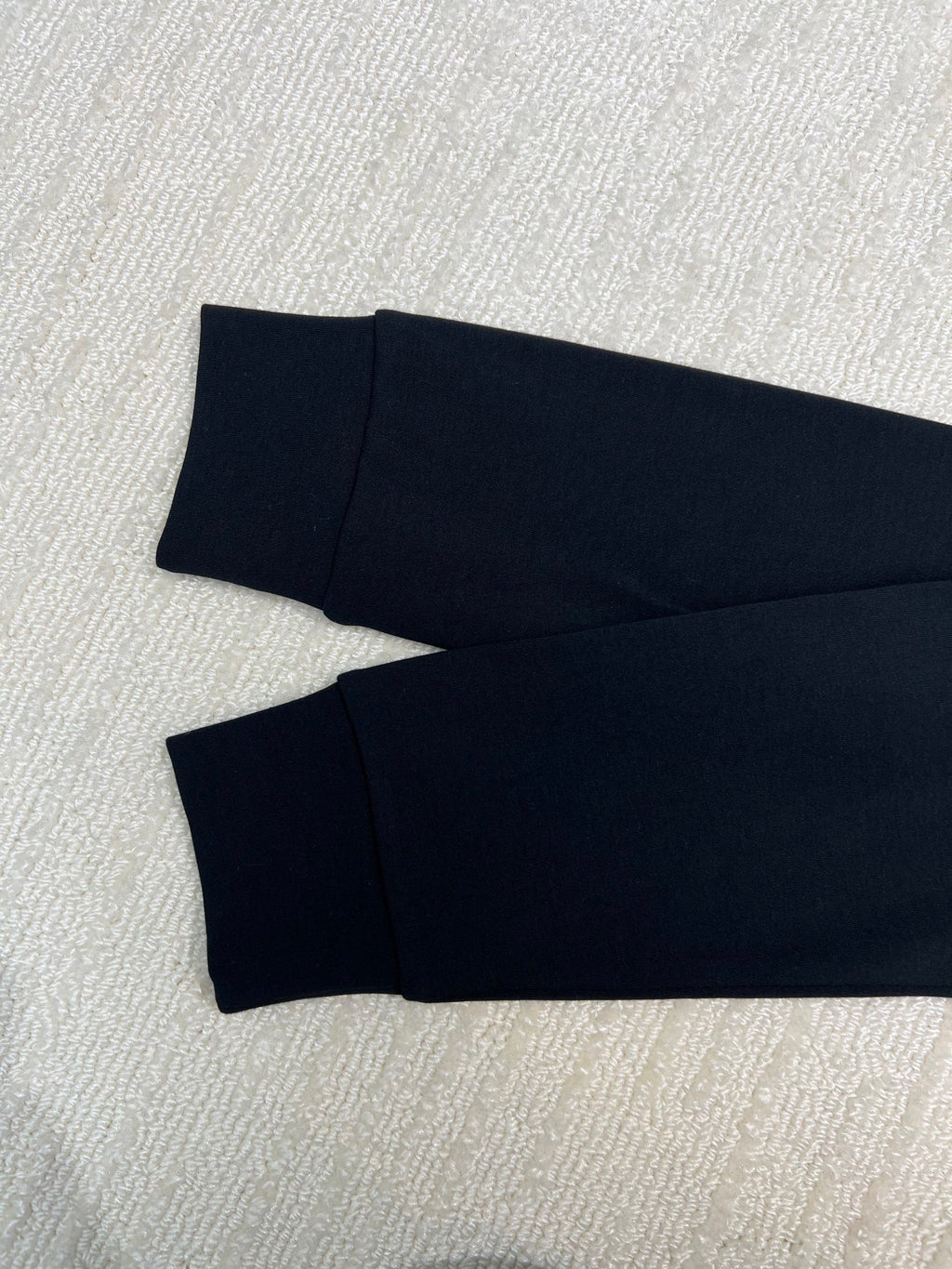Folded dark long-sleeve sweatshirt with matching cuffs, laid flat