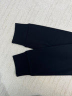 Folded dark long-sleeve sweatshirt with matching cuffs, laid flat