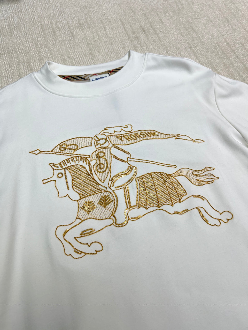 White long-sleeve shirt with large gold horse-and-rider graphic on the chest