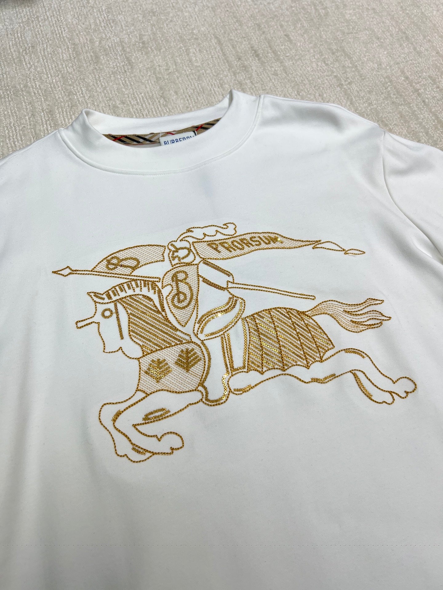 White long-sleeve shirt with large gold horse-and-rider graphic on the chest